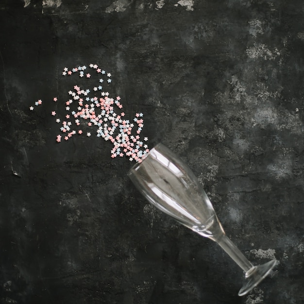 Champagne glass full of coloured glitter on dark background Creative minimal party concept