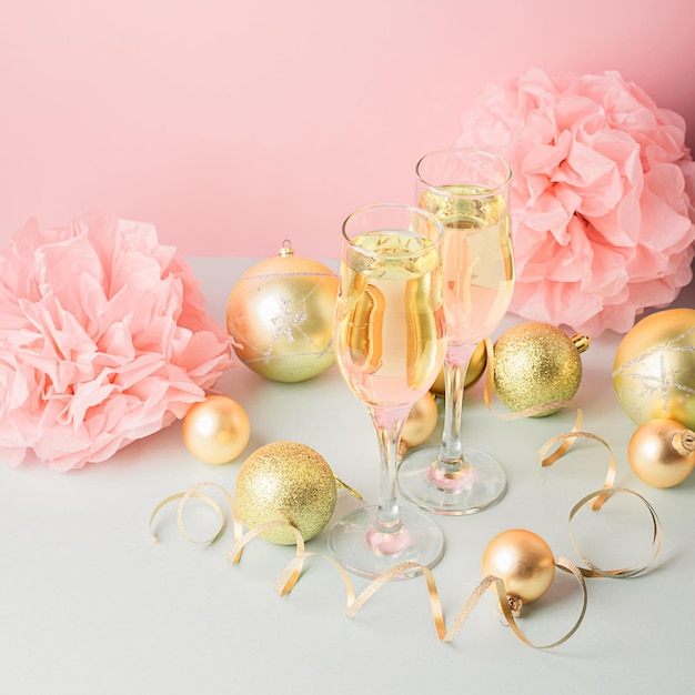 Champagne in glass goblets gold balloons stars serpentine a pastel delicate pink background New year festive concept