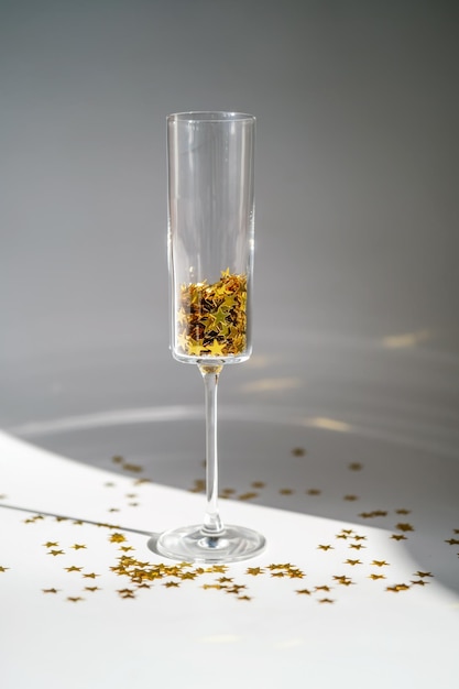 Champagne glass with golden confetti and sparkler on a white background