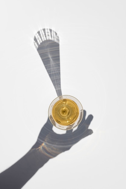 Champagne glass with long hard shadow of hand