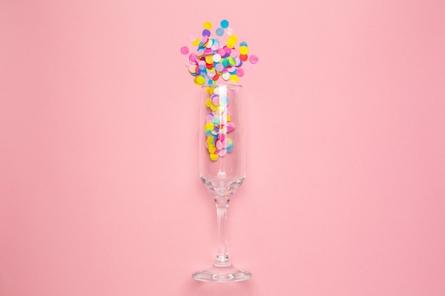 Champagne glass with multi-colored confetti on pink 