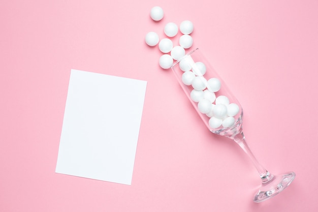 Champagne glass with white balls and card on pink  