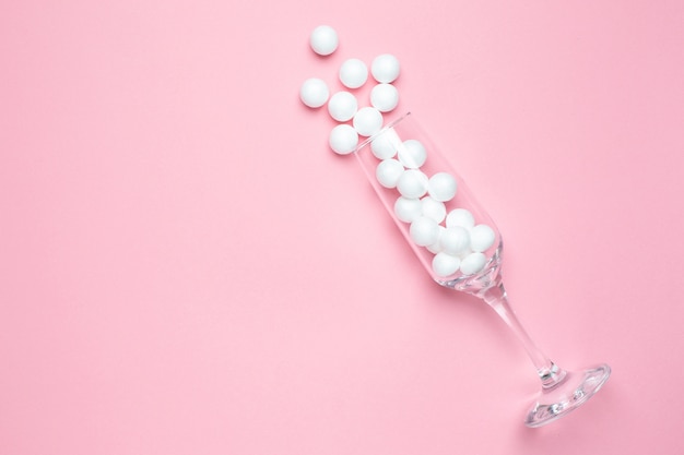 Champagne glass with white balls on pink   minimal style.