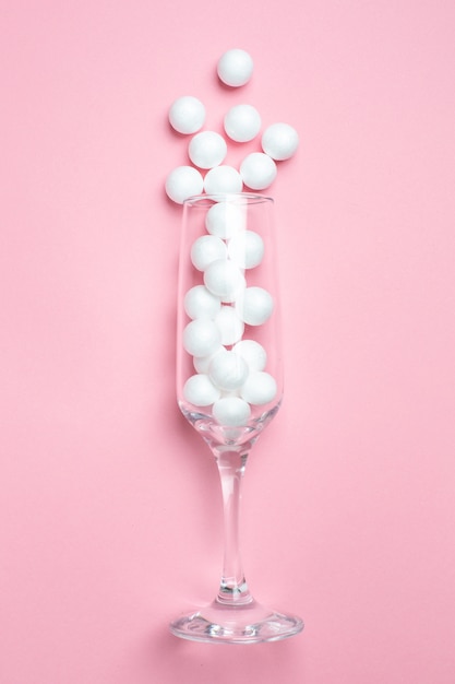 Champagne glass with white balls on pink   minimal style.