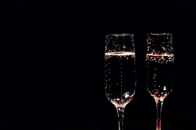 Champagne glasses and decor for Valentines day stand on black background 
