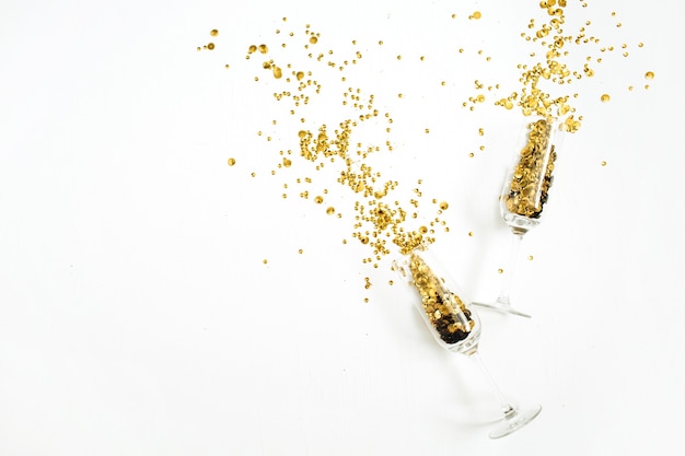 Photo champagne glasses with golden confetti tinsel on white