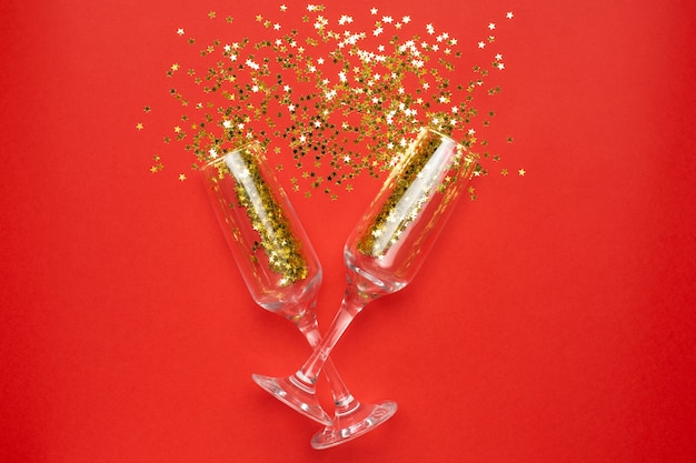 Champagne glasses with golden stars confetti, christmas and new year concept