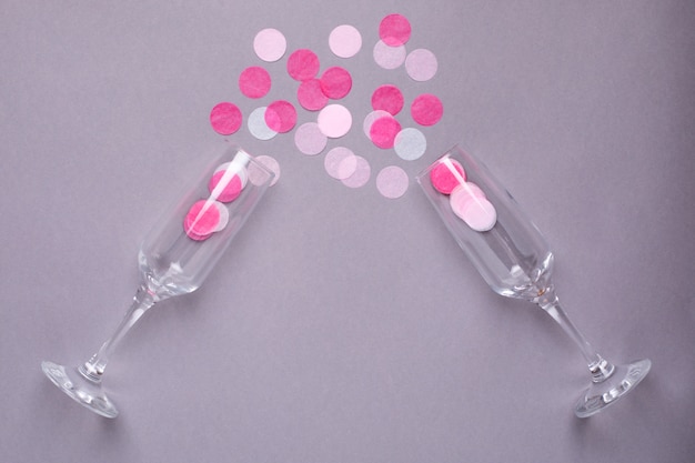 Champagne glasses with pink confetti on a gray  