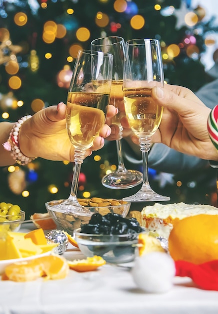 Champagne in hand against the background of the Christmas tree. People. Selective focus. Holiday.