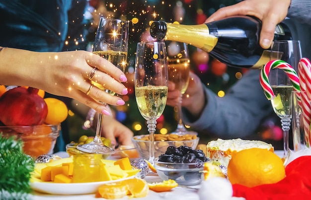 Foto champagne in mano sullo sfondo dell'albero di natale. persone. messa a fuoco selettiva.