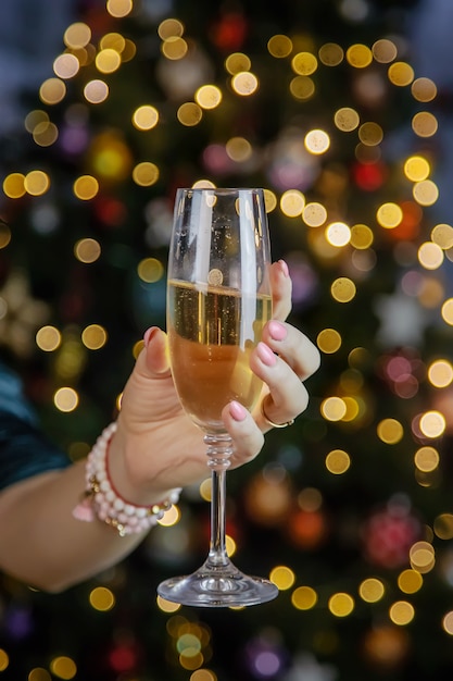 Champagne in mano sullo sfondo dell'albero di natale. messa a fuoco selettiva. vacanza.