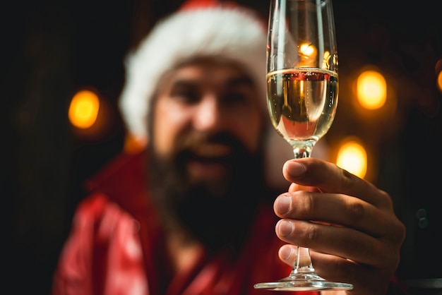 Champagne in hands festive happy men. Santa Claus wishes Merry Christmas. Santa is holding champagne in his hands.