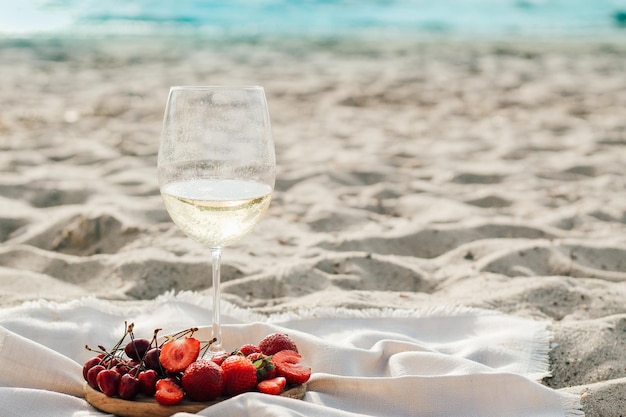 Champagne met fruitschaal met aardbeien en kersen op een picknick op het strand