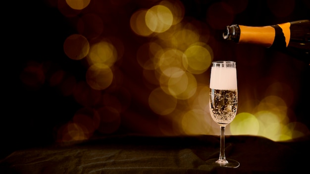 Photo champagne pouring in glass with bokeh effect