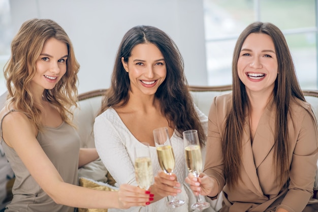 Champagne. Three young girls having a hen party and drinking champagne