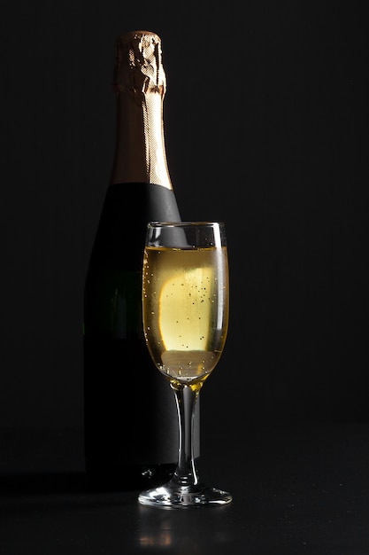 Champagne wine glass and bottle on black background