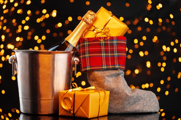 Foto champagnefles en christmas stocking met geschenken tegen garland