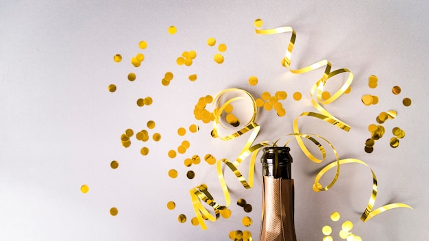 Champagnefles met gouden confetti en streamers op witte achtergrond