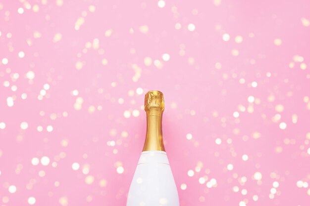 Champagnefles op roze achtergrond. kerstmis, verjaardag, vrijgezellenfeest of huwelijksconcept. plat lag stijl. bovenaanzicht, kopieer ruimte.