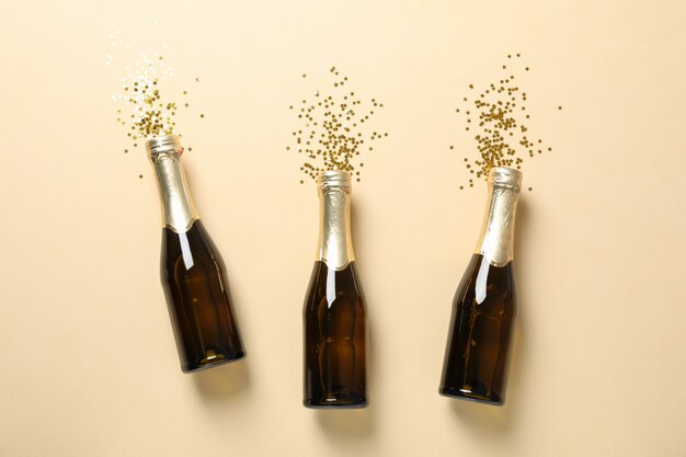 Champagneflessen en glitter op beige, ruimte voor tekst