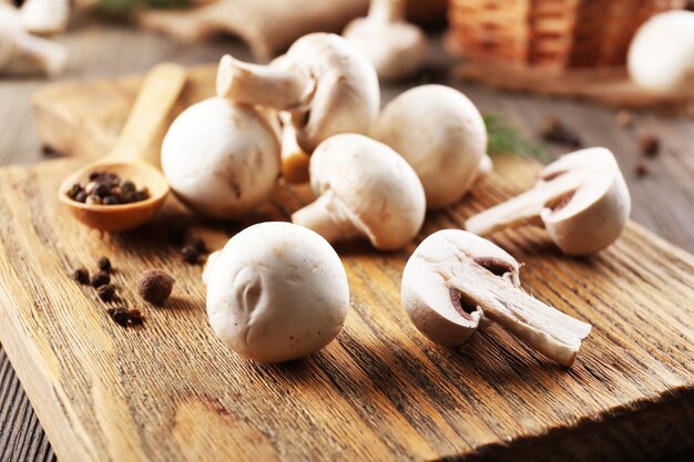 Champignon mushrooms a spoon and spices on wooden background