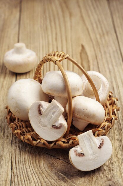 Champignon in wicker basket on wooden background