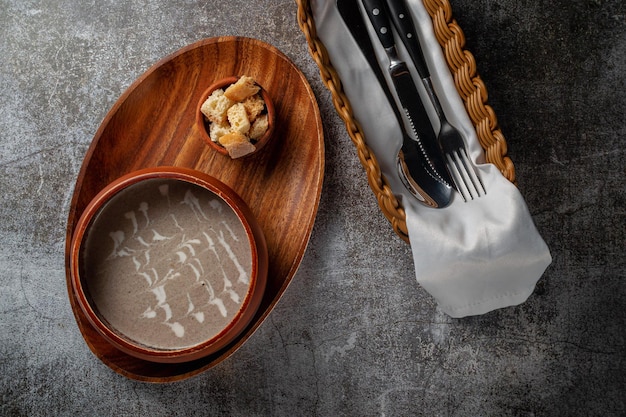 Champignonpuree in een houten kom op een dienblad met broodkruimels tegen een grijze stenen tafel