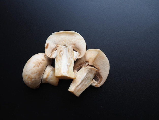 Champignons on a black background Sliced and whole fresh uncooked raw mushrooms Cooking mushrooms with a recipe