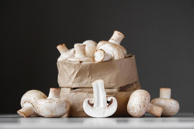 Champignons champignons in papieren zak op een witte houten tafel op een donkere achtergrond