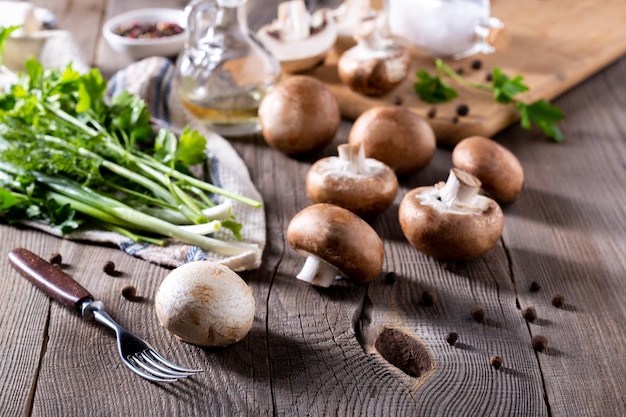 Champignons, dille, peterselie, groene uien op een houten tafel. Producten voor de bereiding van champignongerechten