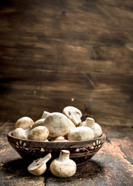 Champignons in de kom. Op een houten achtergrond.