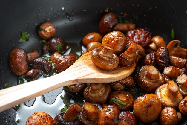 Champignons in zonnebloemolie in een koekenpan houten lepel met gebakken champignons pan van gebakken champignons