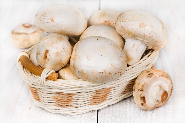 Champignons in a wicker basket on a wooden background