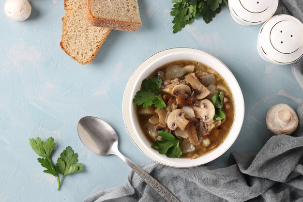 Champignonsoep van champignons en linzen in een witte plaat op een lichtblauwe achtergrond, uitzicht van bovenaf