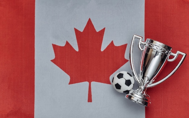 Champion cup with soccer ball on Canada flag. Sport competitions