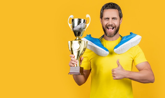 Foto campione uomo vincitore in studio copia foto spaziale di campione uomo vincatore con sneakers campione uomo vinitore isolato su giallo campione uomo vittorioso sullo sfondo