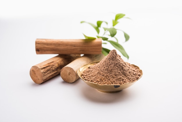 Chandan or sandalwood powder with sticks and green leaves