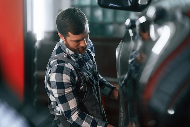 Changing the tire of the car Man in uniform is working in the auto salon