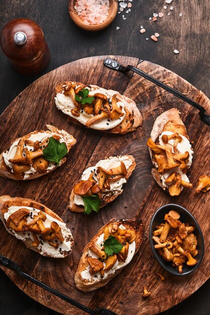 Chanterelle sandwiches with cheese. Open faced sandwich with creamy cheese, seasonings and pepper and fresh parsley on an old wooden background. Mock up. Top view.