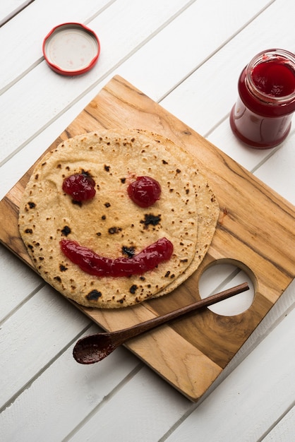 Chapati Roll with Tomato Ketchup Or Fruit Jam Jelly with smily face, indian kid's favourite food menu for school tiffin box, selective focus