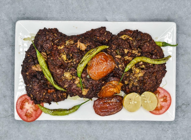 Chapli kabab met citroen en tomaat geserveerd in schotel geïsoleerd op de achtergrond bovenaanzicht van indiase kruiden en pakistaans eten