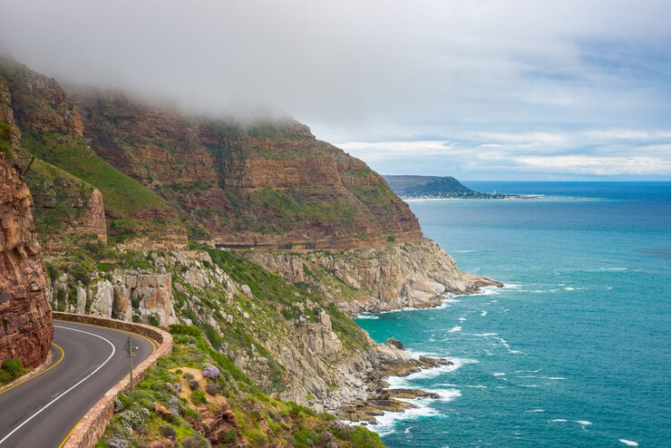 Chapman's Peak Drive, Kaapstad, Zuid-Afrika. Ruwe kustlijn in wintertijd, bewolkte en dramatische hemel, golvende Atlantische Oceaan.