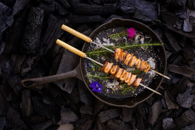 Фото Шар гриль кальмара карамелизированный и холодный вкус, на фоне древесного угля.