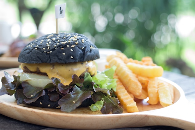 charcoal cheese burger on wooden plate with fresh french fried 