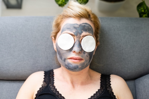 Charcoal face mask or black clay mud. beautiful woman with
black mask on her face, close up studio head shot. natural cosmetic
concept.