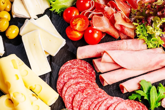 Charcuterie antipasti platter with assortment of salami cheese camembert and olives on wooden table