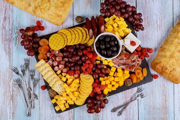 Charcuterie assortment, cheese, olives, fruits and prosciutto on wooden table