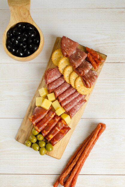 Charcuterie board Board with snacks Cold cuts Sausages cheese crackers and olives are beautifully arranged Rustic style Closeup Copy space