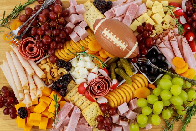 Charcuterie board with cheese, grape, ham and crackers. American football meal.