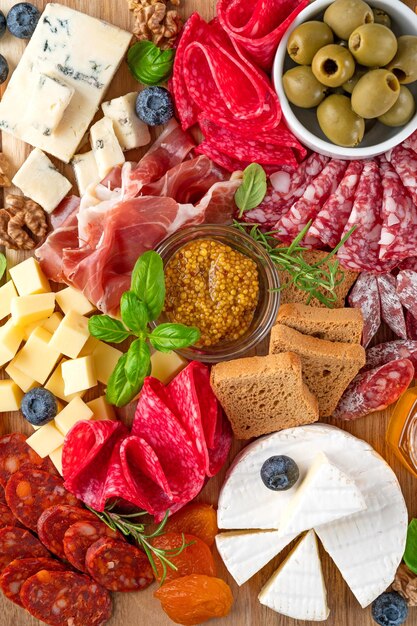 Charcuterie board with a variety of cheeses meat delicacies\
nuts mustard and herbs